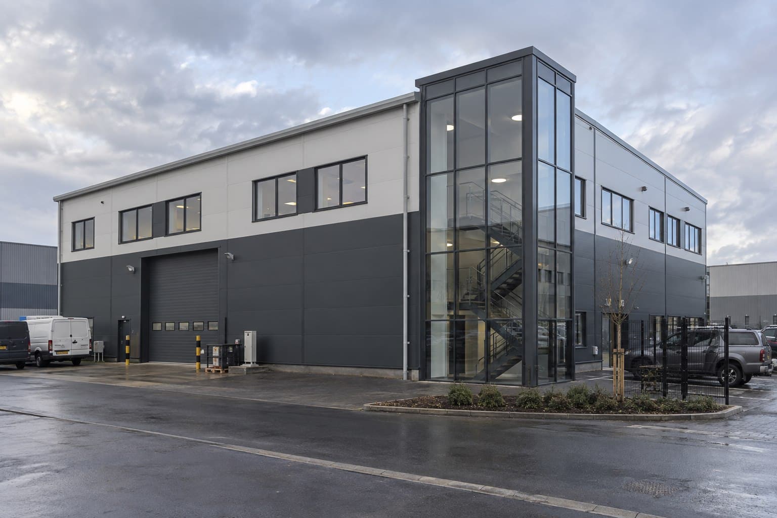 Two-storey prefabricated steel building with office windows and warehouse access