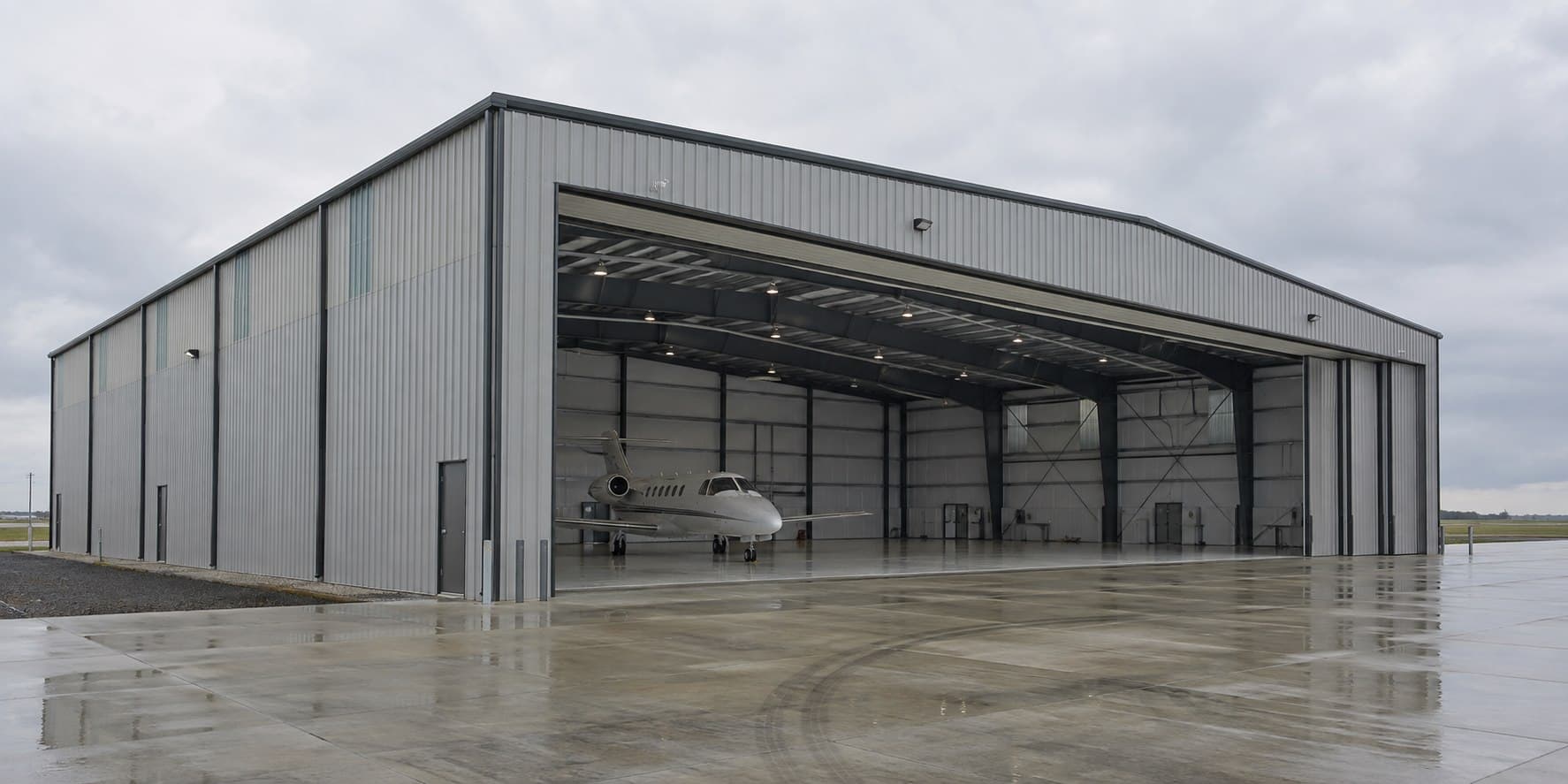 Completed steel aircraft hangar photographed from a wet airport apron